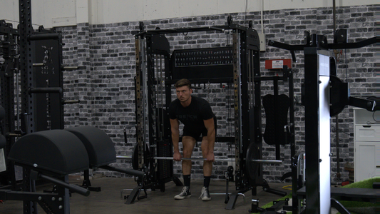 Athlete setting up for a barbell deadlift inside a gym featuring French Fitness all-in-one training equipment and rigs.